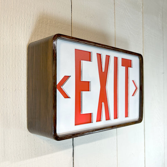 Eames inspired exit sign with red letters on a white background, mounted on a wall.