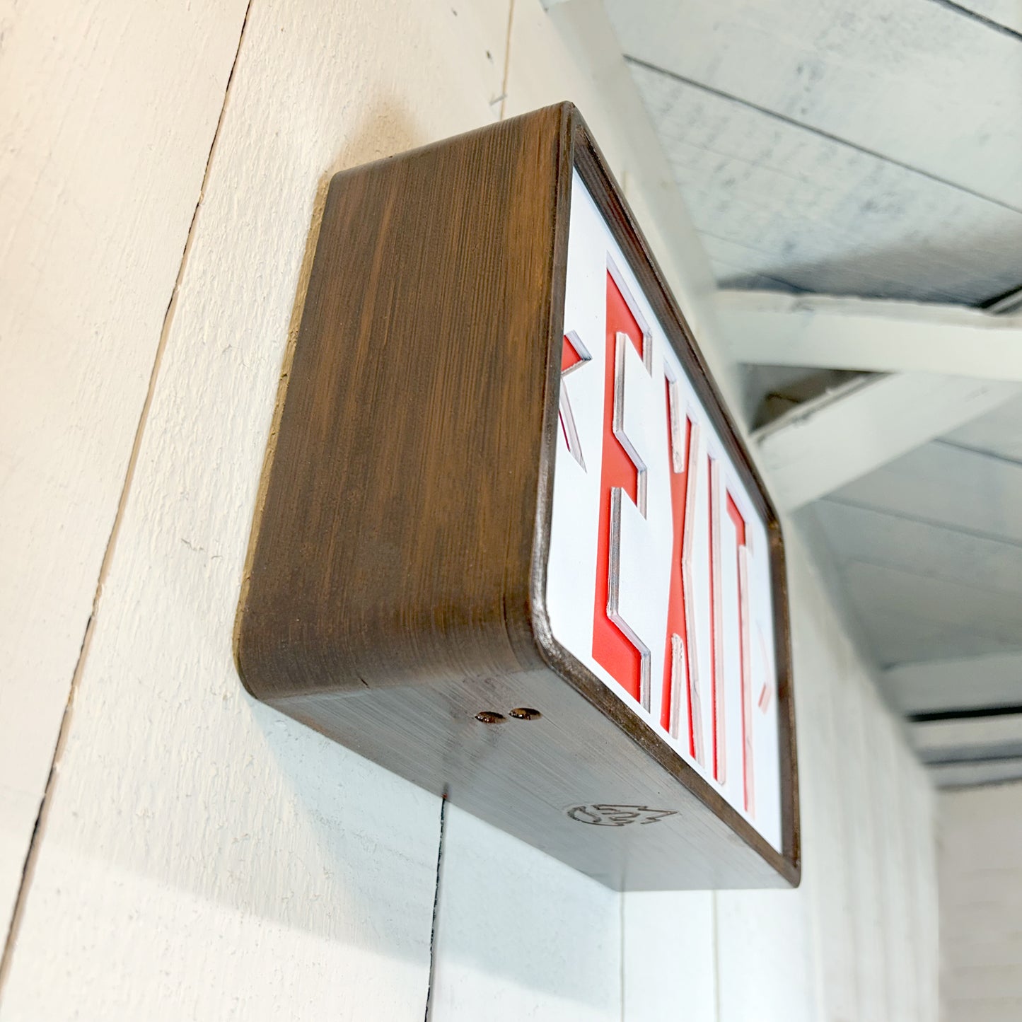 Wooden-framed exit sign on a white wall